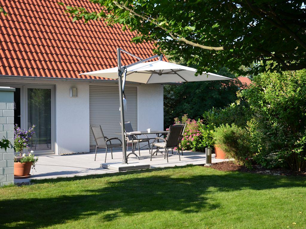 Gartenansicht eines Einfamilienhauses mit Terrasse und Sonnenschirm